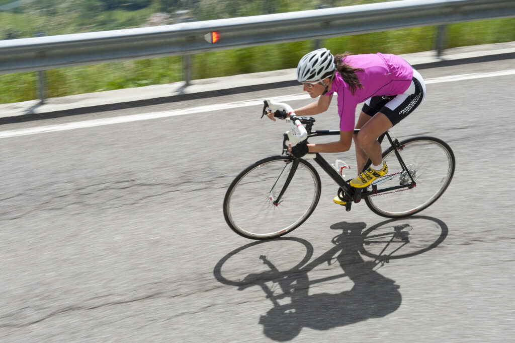 A woman cycle racer taking a corner on a mountain descent