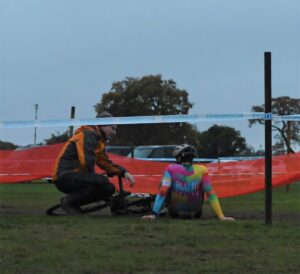 A cyclocross racer finds some post-race recovery sitting on the ground